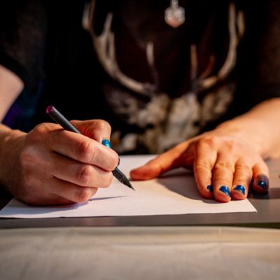 One hand lies on the paper while the other one is holding a pencil, ready to write